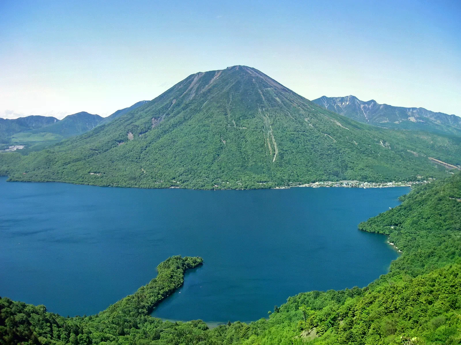 從高處俯瞰中禪寺湖與後方的男體山，湖面湛藍、岸邊綠意（夏季景觀）