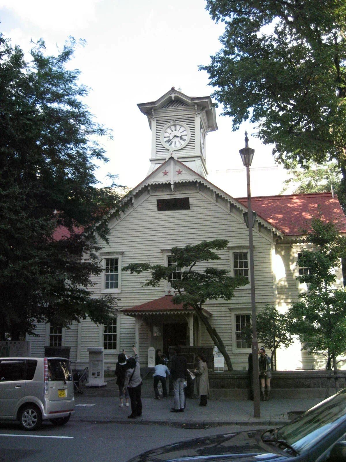 札幌時計台白色木造建築與中央鐘樓，周圍有樹木。