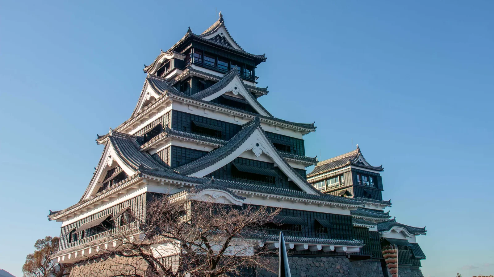 熊本城天守與石垣仰角，晴空背景