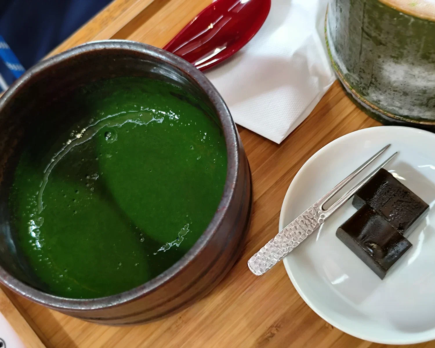 深綠色抹茶旁，白盤放有數塊深色茶點