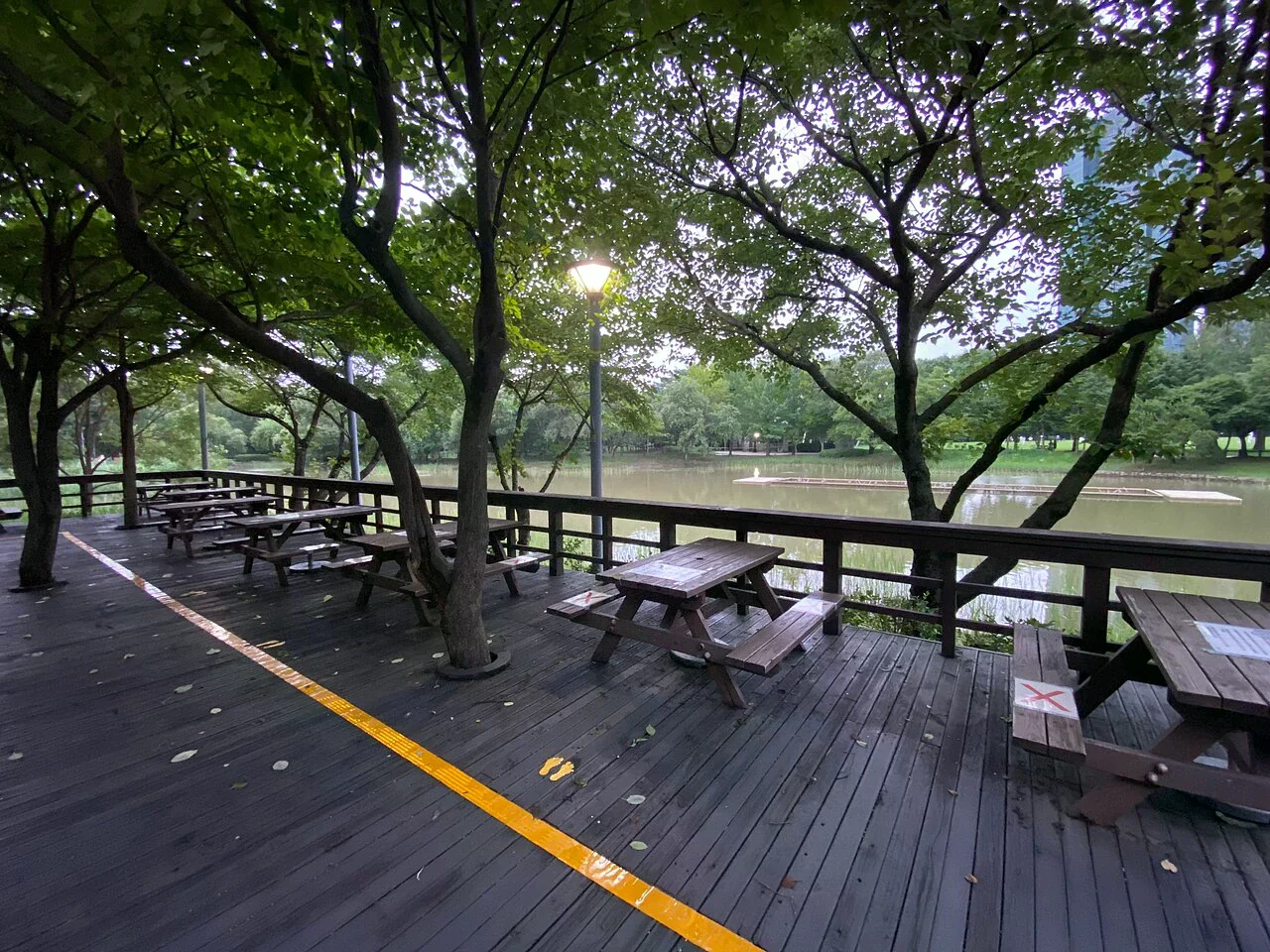 首爾林樹蔭步道旁的木棧平台與桌椅,遠處可見水景